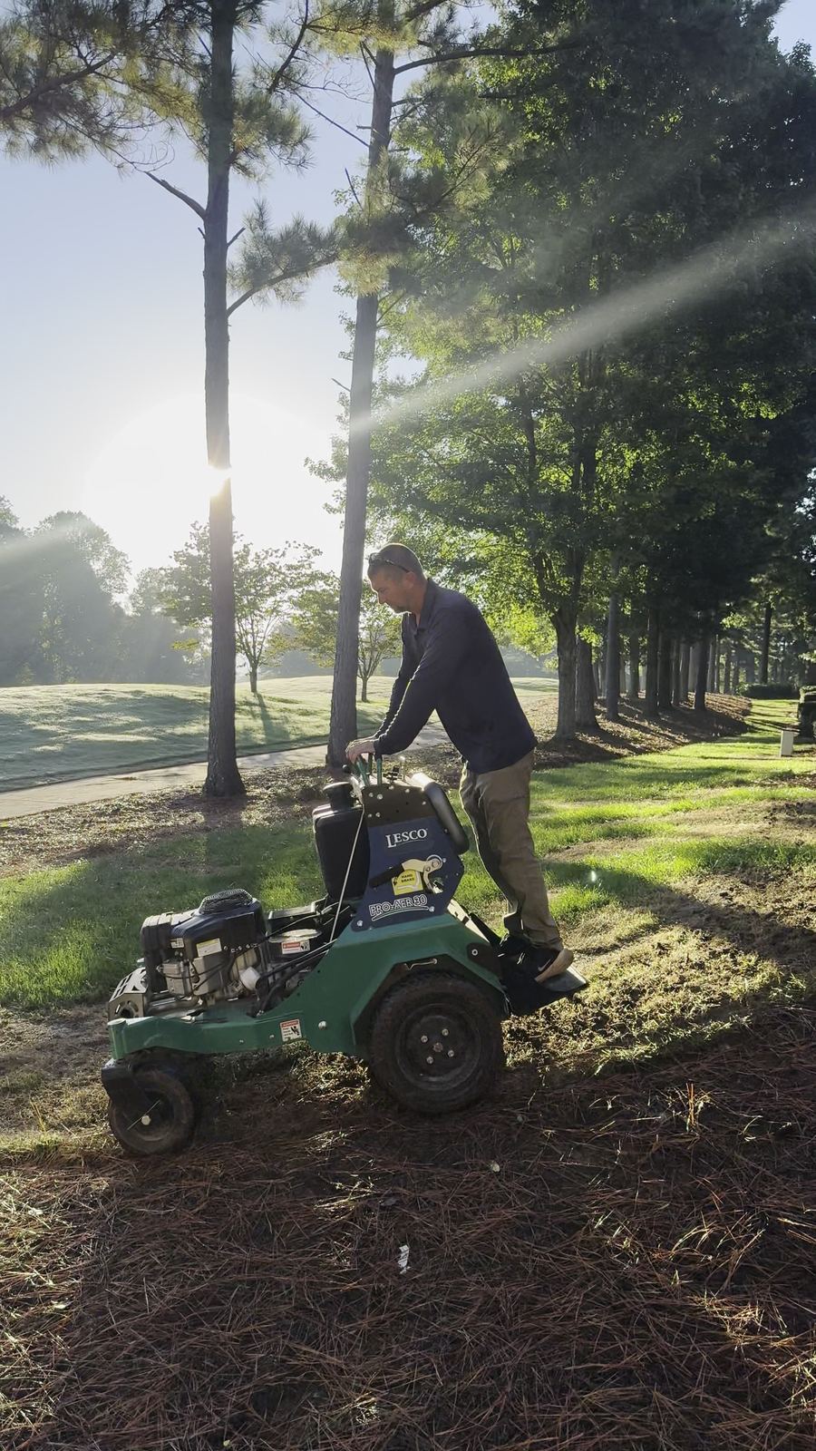 Technician running a core aerator on a lawn
