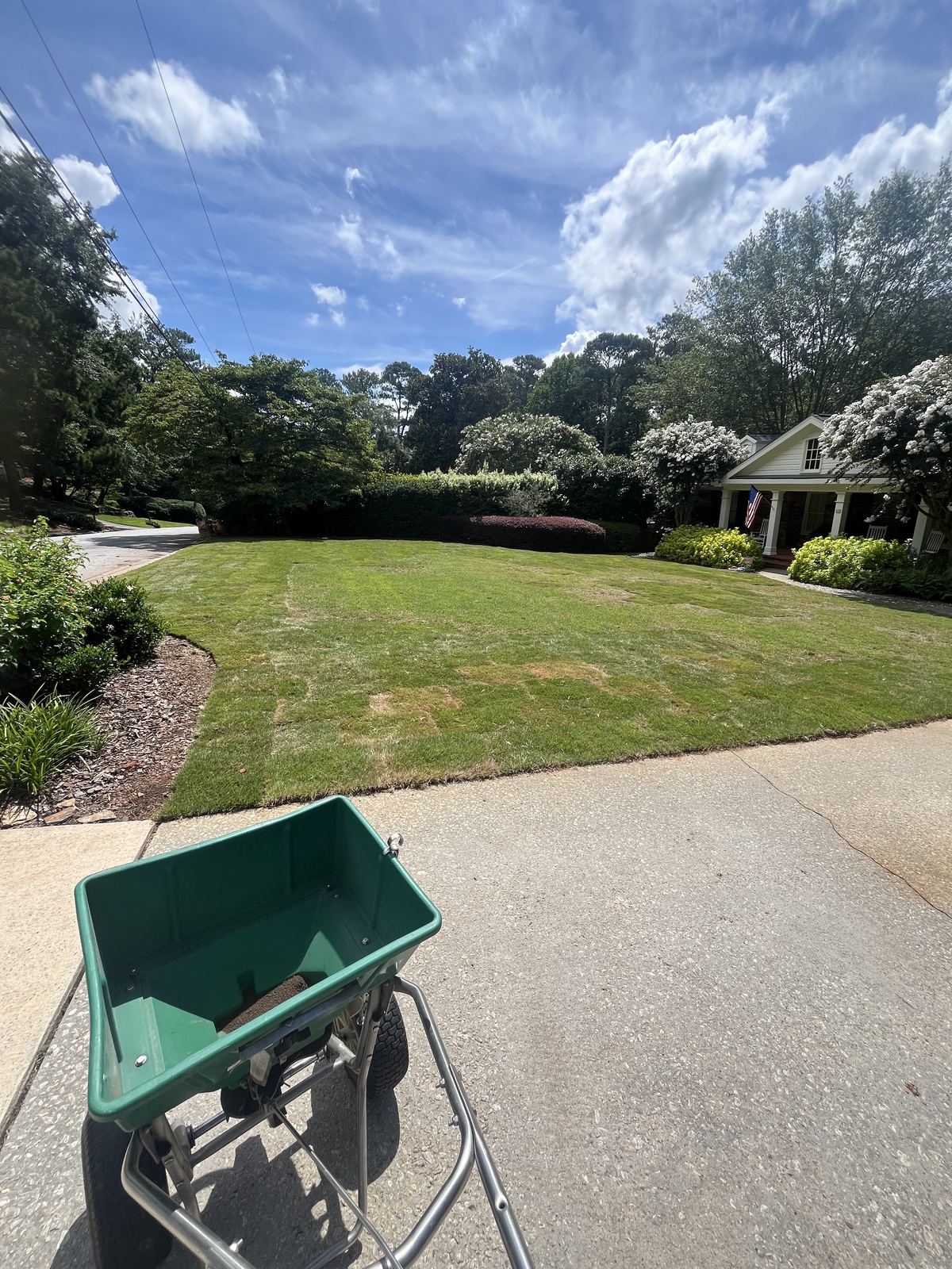 Fertilizer spreader at the edge of a freshly treated lawn